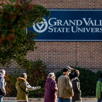 Group of campus tour in front of building that has a sign "Grand Valley State University"